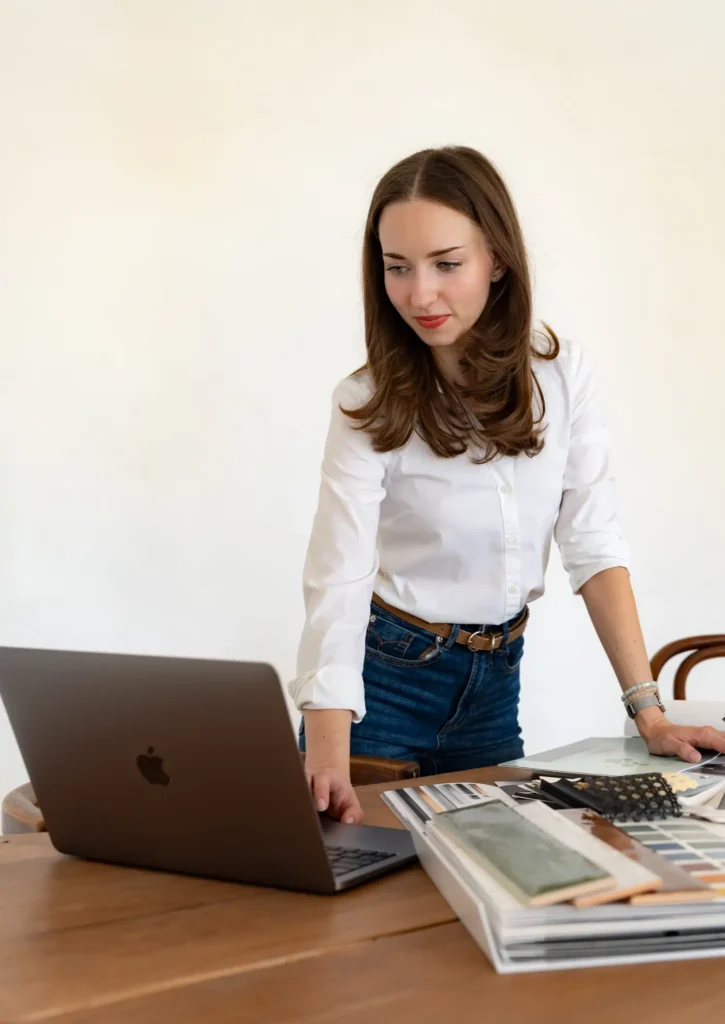 Belsőépítész laptop előtt dolgozik anyagmintákkal és színpalettákkal